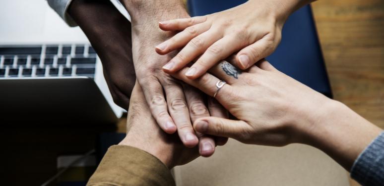 Image of hands on top of each other to symbolize cooperation 